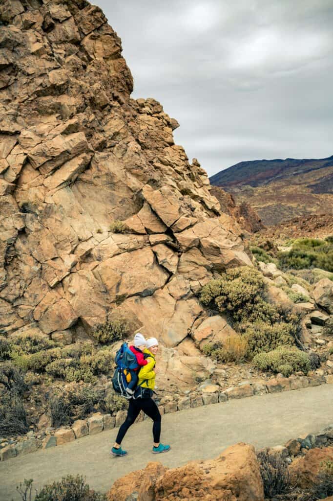 Happy mother with little boy travelling in backpack